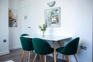 a dining room with a white table and green chairs at Modern Townhouse Apartment with FREE Parking, Wifi & Netflix in Stratford-upon-Avon