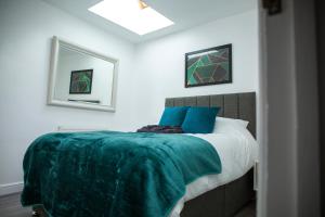 a bedroom with a bed with a green blanket on it at Modern Townhouse Apartment with FREE Parking, Wifi & Netflix in Stratford-upon-Avon