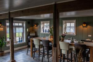 Ursem的住宿－De Martha Hoeve，一间拥有绿色墙壁和桌椅的用餐室