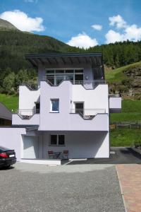 ein weißes Haus mit einem Hügel im Hintergrund in der Unterkunft Apartment Berkristall - SOE268 by Interhome in Sölden