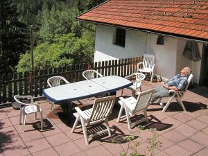 an older man sitting at a table and chairs at Holiday Home Jagdhaus Strengen - SNN100 by Interhome in Oberriefen