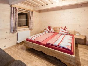ein Schlafzimmer mit einem Bett in einem Zimmer mit Holzwänden in der Unterkunft Chalet Grimmingblickhütte - GBM301 by Interhome in Unterlengdorf