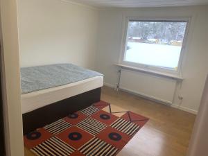 een slaapkamer met een bed, een raam en een tapijt bij Beutiful house with large garden . in Lilla Edet