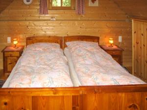een bed in een houten kamer met twee lampen op tafels bij Holiday Home Kunzhof - TFN110 by Interhome in Winklern