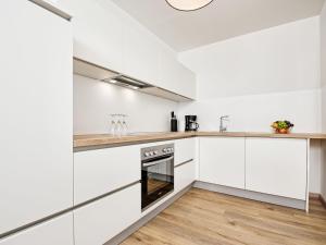a kitchen with white cabinets and wood floors at Apartment Deutschbauer - FAK100 by Interhome in Egg am Faaker See