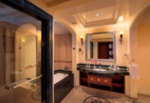 a bathroom with a tub, sink, and mirror at Premier Le Reve Hotel & Spa Sahl Hasheesh - Adults Only 16 Years Plus in Hurghada