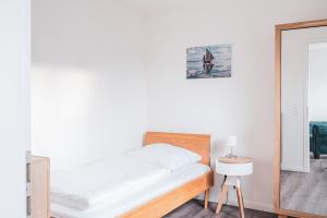 biała sypialnia z łóżkiem i lustrem w obiekcie Westwind - Haus 1 w Prerowie