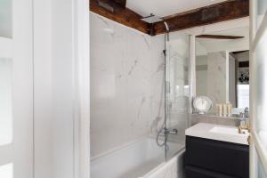 a white bathroom with a shower and a sink at Hôtel Du Jeu De Paume in Paris