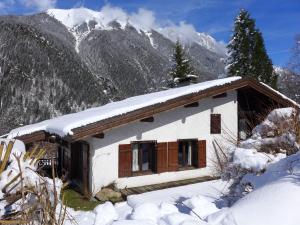 una pequeña casa en la nieve con montañas en el fondo en Chalet L'Piri by Interhome, en Chamonix-Mont-Blanc