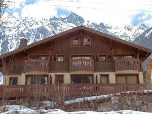 a large wooden house with mountains in the background at Apartment Le Krystor by Interhome in Chamonix