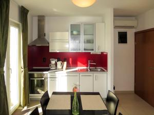 kuchnia ze stołem i czerwoną ścianą w obiekcie Apartment Milevoj - RAC157 by Interhome w Rabacu
