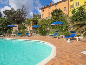 a swimming pool with chairs and umbrellas and a building at Apartment Aida by Interhome in Massarosa