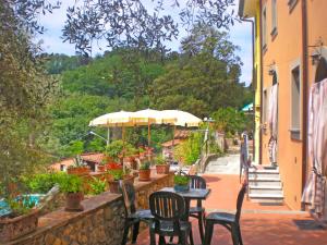 een patio met tafels en stoelen en een parasol bij Apartment Aida by Interhome in Massarosa