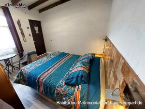 1 dormitorio con 1 cama y 1 mesa en una habitación en Hostal Atacama Ancestral, en San Pedro de Atacama