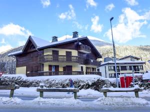 a house in the snow with two benches in front at Apartment L'Hermine by Interhome in Les Houches