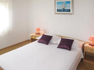 a white bed with two purple pillows in a bedroom at Holiday Home Vesna - ZAD105 by Interhome in Diklo