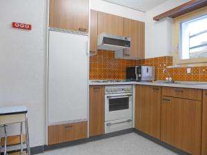 ツェルマットにあるApartment Richemont by Interhomeのキッチン(木製キャビネット、白い冷蔵庫付)