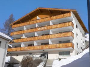 ein weißes Apartmenthaus mit Holzbalkonen darauf in der Unterkunft Apartment Viscaria-2 by Interhome in Zermatt