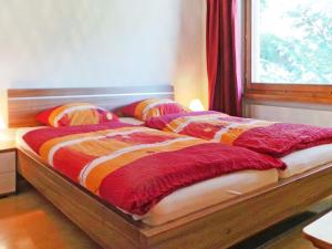 uma cama com cobertores vermelhos e laranja e uma janela em Apartment Memory by Interhome em Zermatt