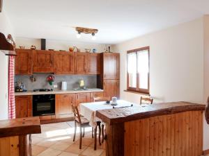 una cocina con armarios de madera y una mesa con sillas. en Holiday Home Quang - GZO200 by Interhome, en Garzeno