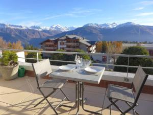 a table and chairs on a balcony with mountains at Apartment Jeanne d'Arc-5 by Interhome in Crans-Montana