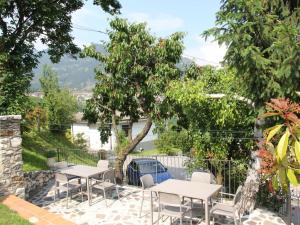 patio ze stołami, krzesłami i drzewem w obiekcie Apartment La Tartufaia-6 by Interhome w Tremosine Sul Garda
