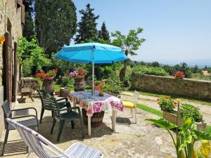 a table with a blue umbrella in a garden at Apartment Belvedere-4 by Interhome in Pulicciano