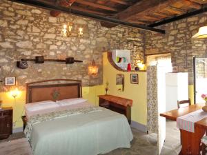 1 dormitorio con cama y pared de piedra en Apartment Belvedere-4 by Interhome, en Pulicciano