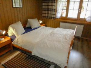a bedroom with a bed with white sheets and a window at Apartment Chalet Doris-1 by Interhome in Grindelwald