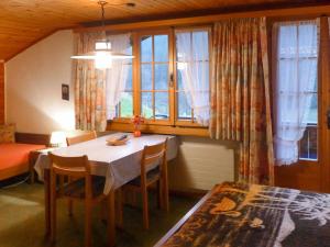 um quarto com uma mesa, cadeiras e janelas em Apartment Chalet Marie Rosa-3 by Interhome em Grindelwald