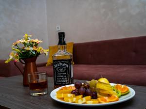 una botella de whisky y un plato de fruta en una mesa en La Corne Hotel Baku en Bakú