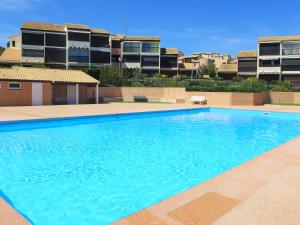 a large blue swimming pool in front of a building at Apartment Les Eaux Vives 1 & 2-7 by Interhome in Saint Pierre La Mer