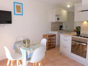 a kitchen with a table and white chairs in a room at Apartment Les Terrasses de la Méditérranée-1 by Interhome in Saint Pierre La Mer