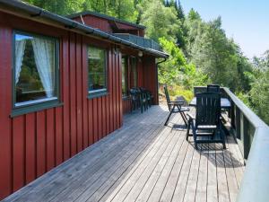 a deck of a red cabin with chairs on it at Holiday Home Haugen - SOW044 by Interhome in Lyngdal