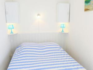 a bedroom with a striped bed with two blue lamps at Apartment Les Balcons de la Méditerranée-15 by Interhome in Narbonne-Plage