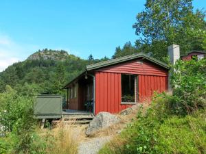 a red shed on a hill with a mountain at Holiday Home Haugen by Interhome in Lyngdal