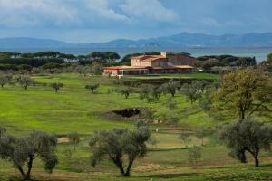 フォッローニカにあるRiva Toscana Golf Resort & SPAの田地の木々のある丘の上の家