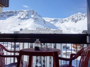 una mesa y sillas en un balcón con una montaña nevada en Apartment Le Prariond - Val Claret-6 by Interhome, en Tignes