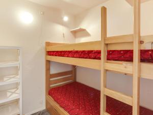 a room with two bunk beds with red sheets at Apartment Pegase Phenix-15 by Interhome in Le Corbier