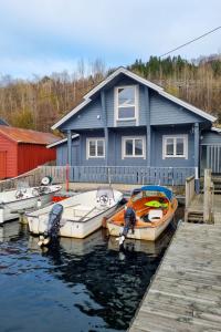 a group of boats docked in front of a blue house at Holiday Home Rorbu - FJS555 by Interhome in Naustdal i Sunnfjord