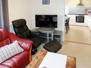 Una sala de estar con un sofá y una mesa con televisión. en Holiday Home Solsvika by Interhome, en Leirvik