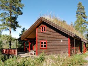 una baita di tronchi con una porta rossa e un portico di Holiday Home Troll - TEM027 by Interhome ad Åmli