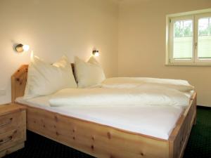 Schlafzimmer mit einem Holzbett mit weißer Bettwäsche und Kissen in der Unterkunft Holiday Home Siedlerhof - HAE180 by Interhome in Haus im Ennstal