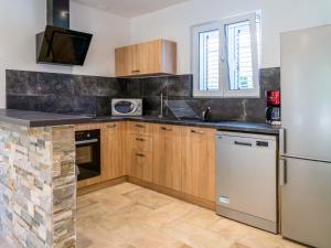 a kitchen with wooden cabinets and a refrigerator at Holiday Home A Suara-2 by Interhome in Ghisonaccia