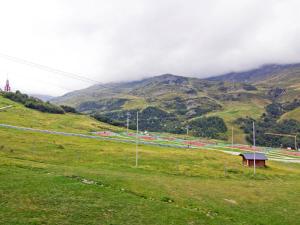 a grassy hill with a road in front of a mountain at Apartment Belleville Caron-7 by Interhome in Les Menuires