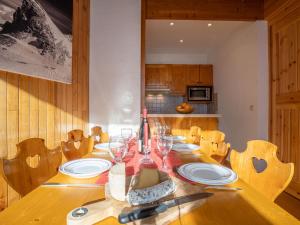 a wooden table with plates and wine glasses on it at Apartment Le Curling B-21 by Interhome in Tignes