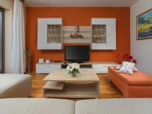 sala de estar con paredes de color naranja y TV de pantalla plana. en Holiday Home Ana by Interhome en Nedeščina