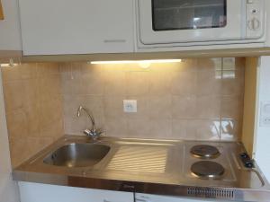 eine Küche mit einer Spüle und einer Mikrowelle in der Unterkunft Apartment Les Olympiques-4 by Interhome in Les Boisses