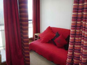 czerwoną kanapę w pokoju z czerwonymi zasłonami w obiekcie Apartment Bellard-2 by Interhome w mieście La Toussuire