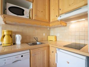 Una cocina con armarios de madera, fregadero y microondas. en Apartment Brelin Evons 401 by Interhome, en Les Menuires